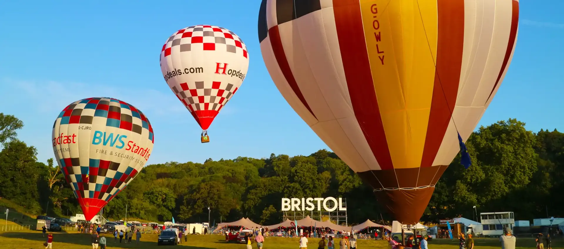 Two hot air balloons on the ground at the Bristol baloon fiesta with a third one in the air