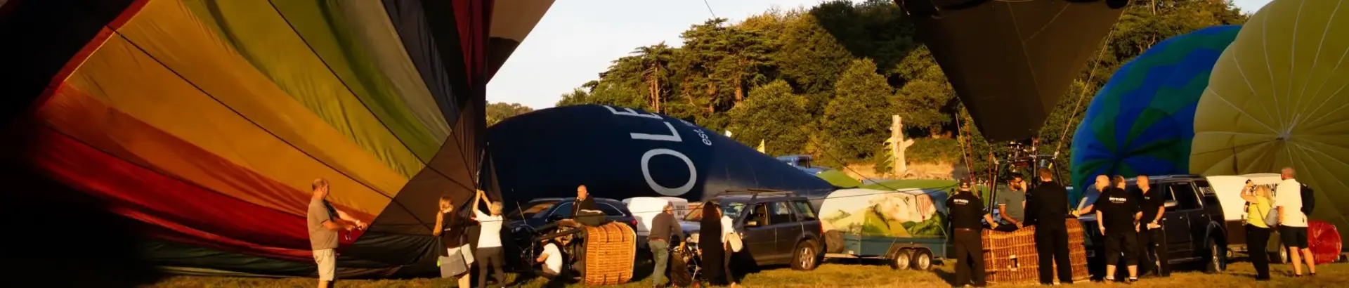 People gathered around semi-inflated hot air balloons